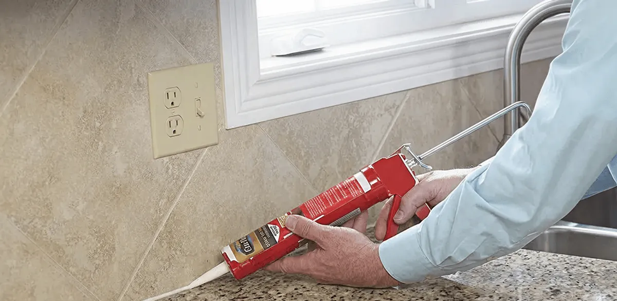 Handyman applying caulk along a kitchen backsplash and countertop seam in Spokane, WA