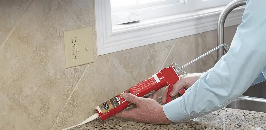 Handyman applying caulk along a kitchen backsplash and countertop seam in Spokane, WA