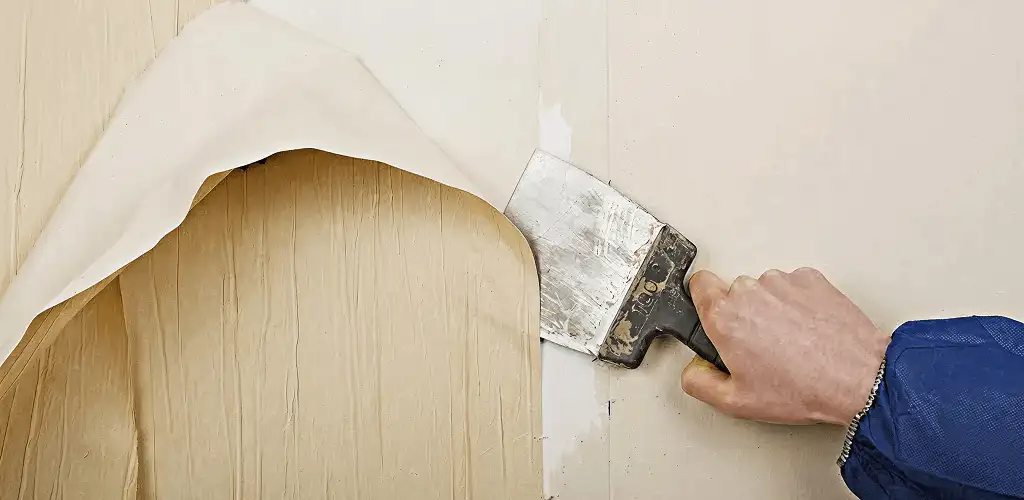 Handyman removing wallpaper with a scraper for wall preparation in Spokane, WA