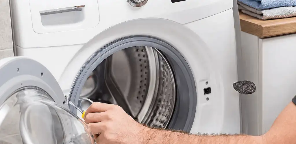 Handyman repairing a front-load washing machine and inspecting the drum in Spokane, WA