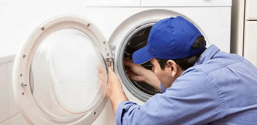 Washing machine repair handyman inspecting a front-load washer drum in Spokane, WA