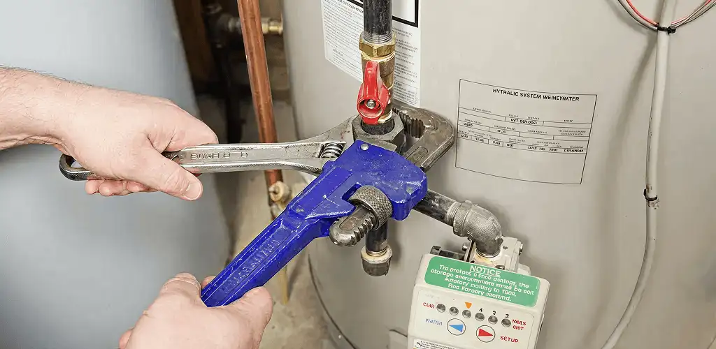Water heater repair technician tightening the shutoff valve and supply line in Spokane, WA